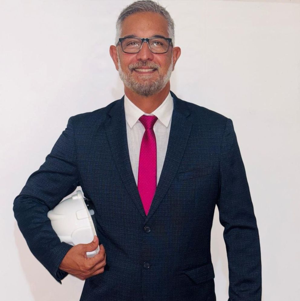 Ritratto dell’ingegnere Márcio Carvalho in abito blu e cravatta fucsia con casco da cantiere; progetto brand e sito REMOD REFORMAS di Natalia Canaletti