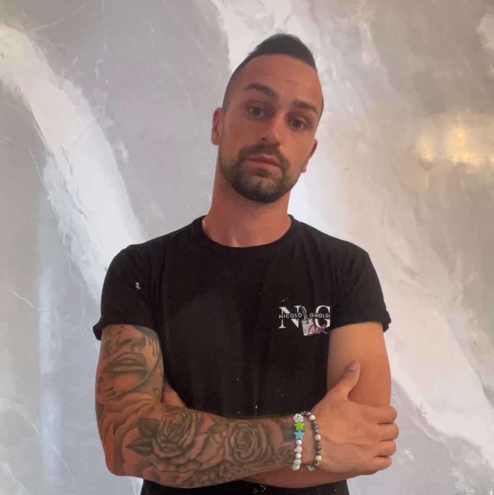 Ritratto di artigiano imbianchino con t-shirt brandizzata NGColor, braccia conserte, su sfondo parete decorativa effetto marmo; portfolio di Natalia Canaletti
